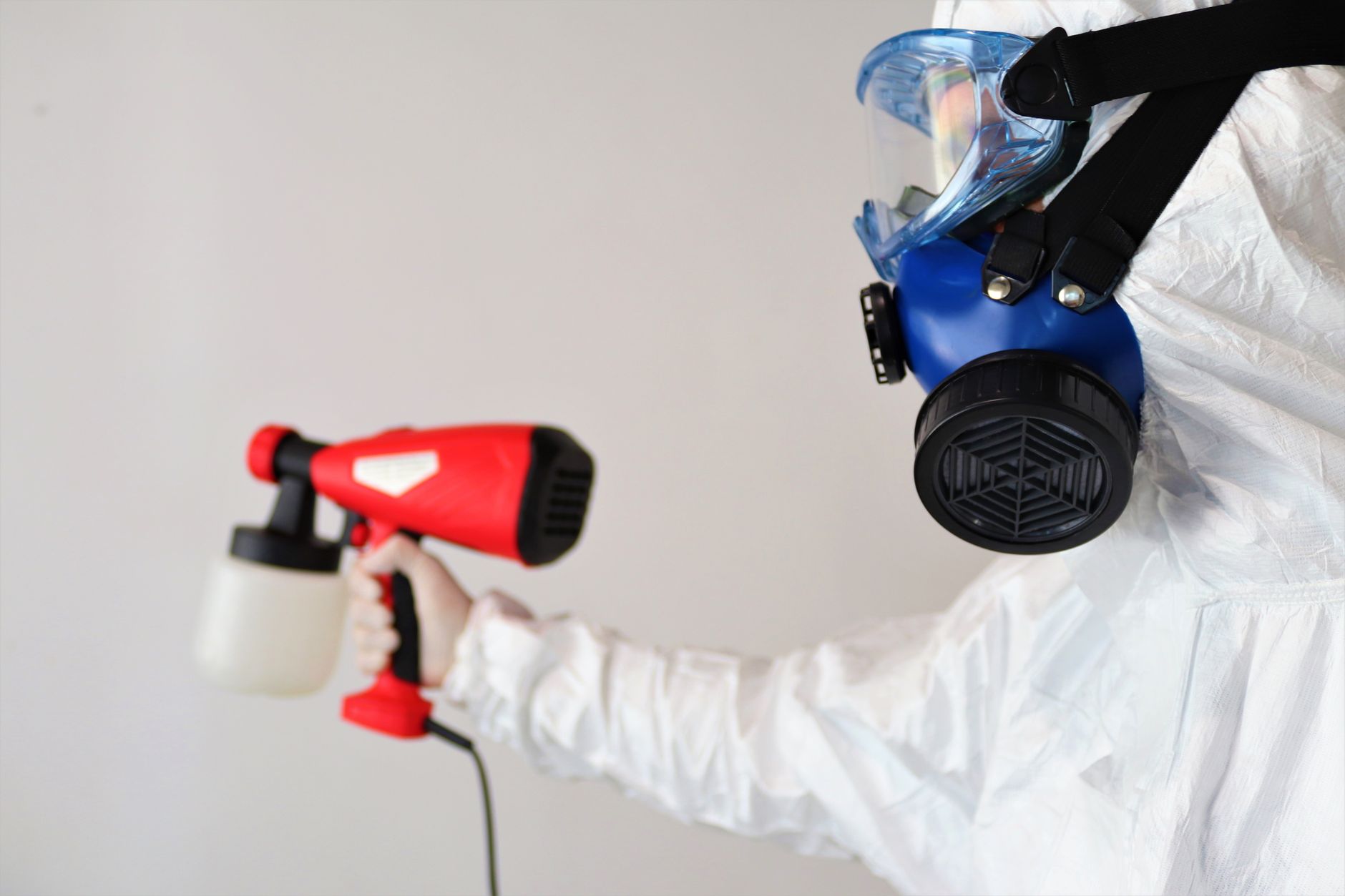 A technician in full PPE inspecting a damp wall for mold in a Flower Mound residential basement.