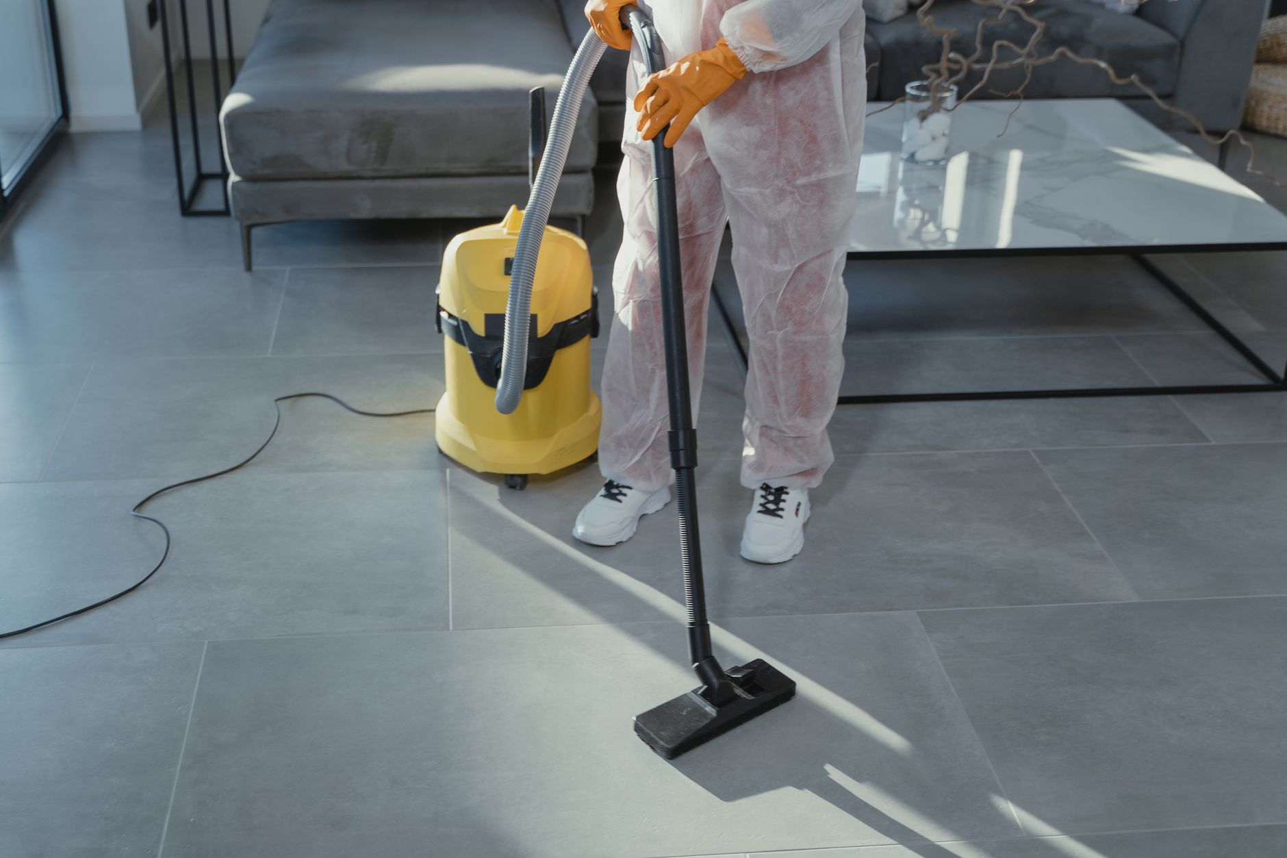 A certified mold remediation technician in full protective gear performing an inspection in a well-lit Carrollton home.